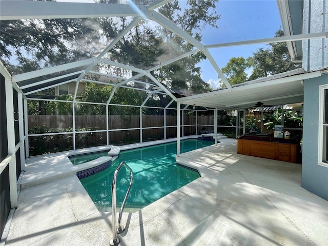 view of pool featuring ceiling fan, a patio, glass enclosure, and an in ground hot tub