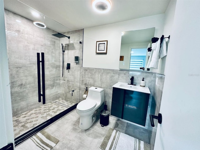 bathroom featuring a shower with shower door, tile patterned flooring, tile walls, toilet, and vanity