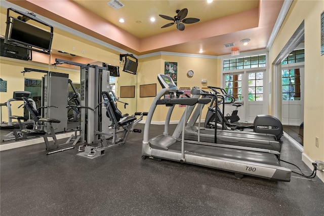 workout area featuring a raised ceiling and ceiling fan