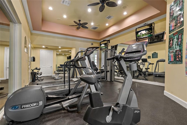 workout area with ceiling fan and a raised ceiling