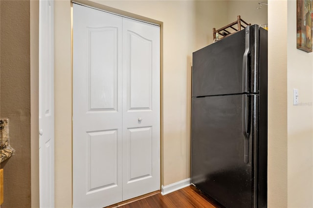 kitchen featuring dark hardwood / wood-style floors and black refrigerator