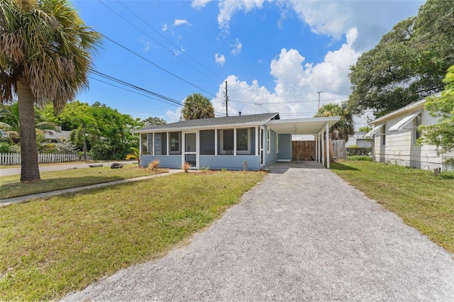 view of front facade with a carport, a sunroom, and a front yard