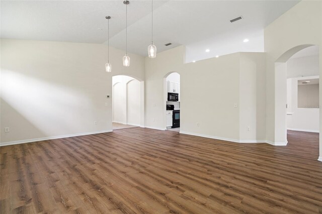 unfurnished living room featuring high vaulted ceiling and dark wood-type flooring