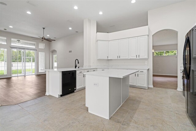 kitchen with white cabinetry, light hardwood / wood-style floors, ceiling fan, kitchen peninsula, and black appliances