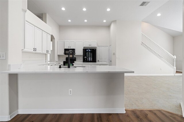 kitchen featuring sink, kitchen peninsula, black appliances, and light wood-type flooring