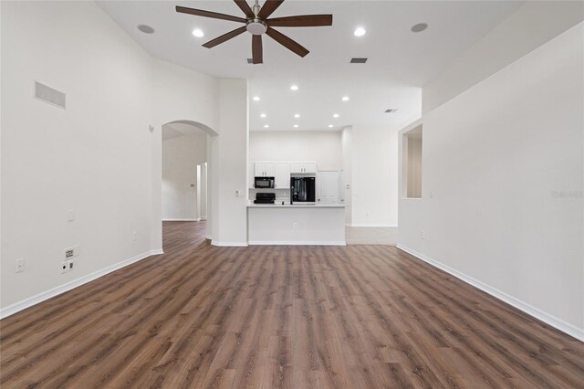 unfurnished living room featuring ceiling fan, wood-type flooring, and a high ceiling