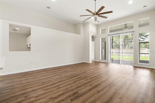 unfurnished living room with hardwood / wood-style flooring, a towering ceiling, and ceiling fan