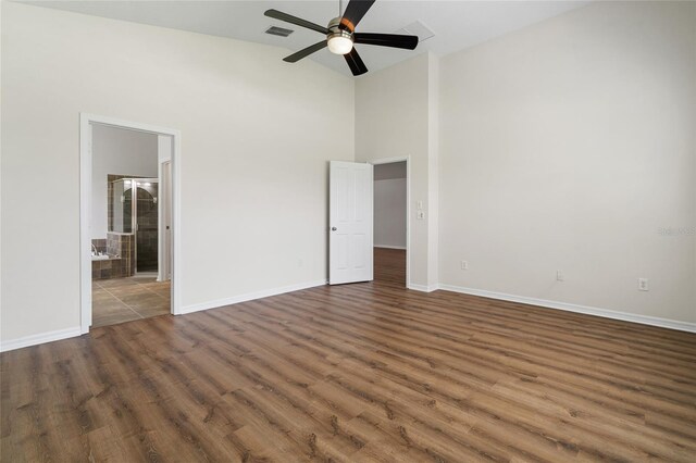 unfurnished bedroom with ceiling fan, high vaulted ceiling, wood-type flooring, and ensuite bath