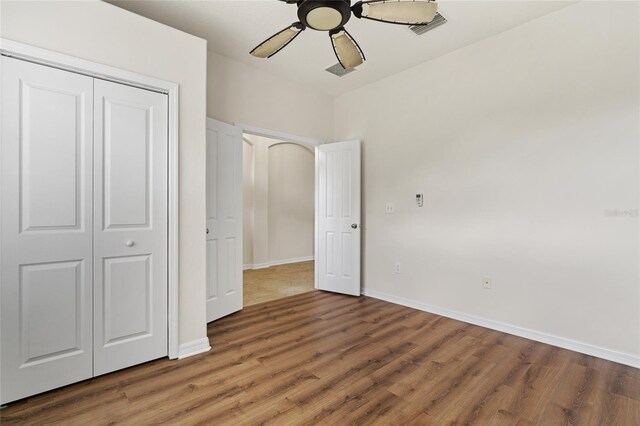 unfurnished bedroom featuring ceiling fan, a closet, and hardwood / wood-style floors