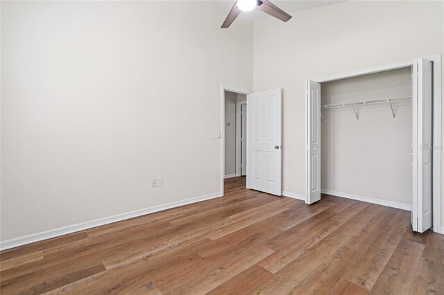 unfurnished bedroom featuring a towering ceiling, hardwood / wood-style floors, and ceiling fan