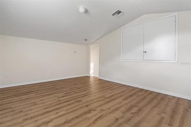 unfurnished living room with vaulted ceiling and light wood-type flooring