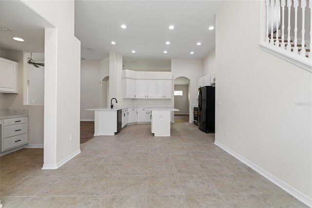 kitchen with light tile patterned flooring, white cabinetry, black refrigerator, ceiling fan, and kitchen peninsula