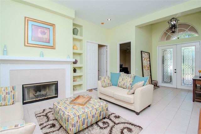 tiled living room featuring built in shelves, a fireplace, french doors, and ceiling fan