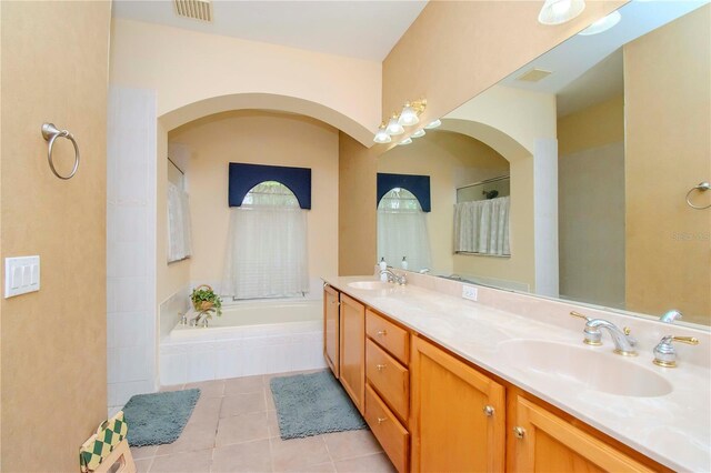 bathroom with tile patterned flooring, dual vanity, and a tub to relax in