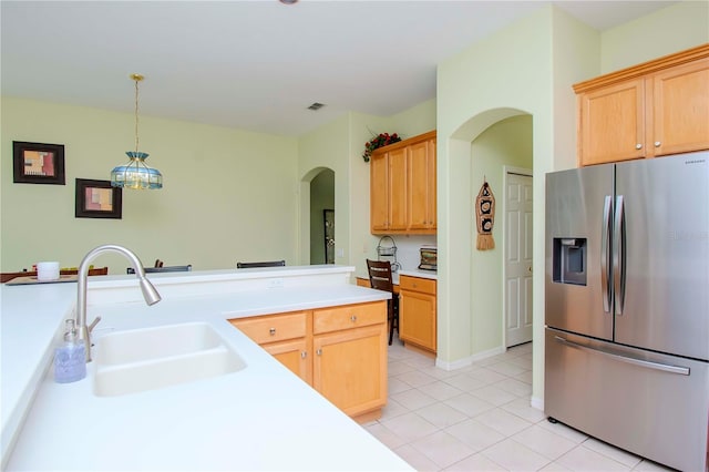 kitchen featuring light brown cabinetry, sink, decorative light fixtures, light tile patterned floors, and stainless steel fridge