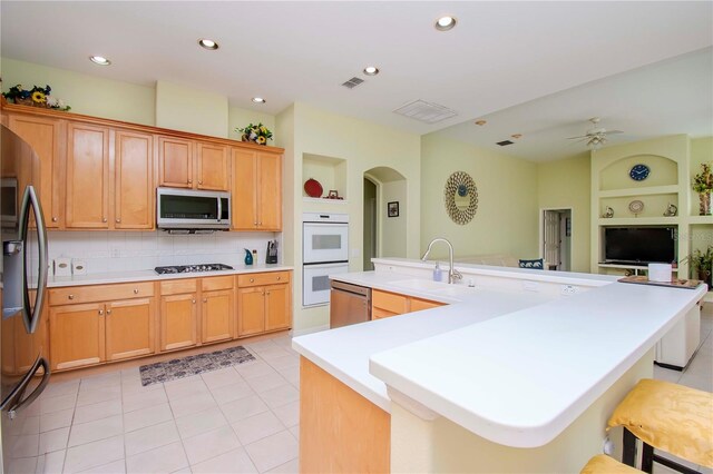 kitchen with light tile patterned flooring, ceiling fan, stainless steel appliances, a spacious island, and sink