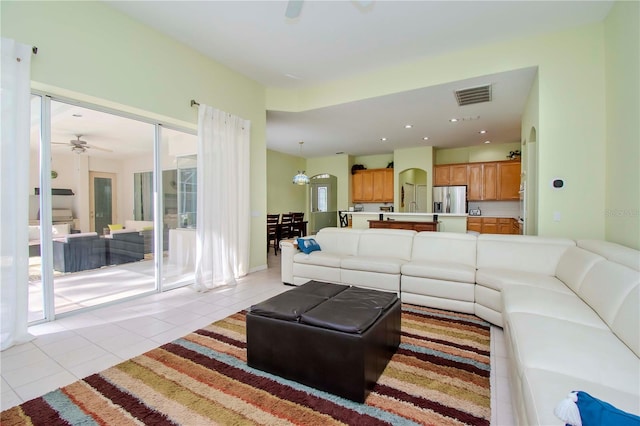 tiled living room featuring ceiling fan with notable chandelier