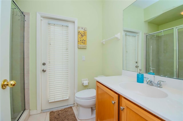 bathroom with vanity, a shower with door, tile patterned flooring, and toilet