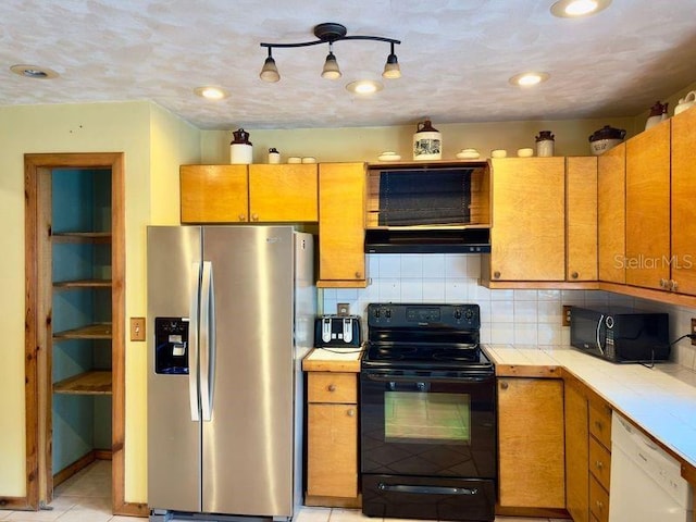 kitchen featuring light tile patterned flooring, rail lighting, tasteful backsplash, and black appliances