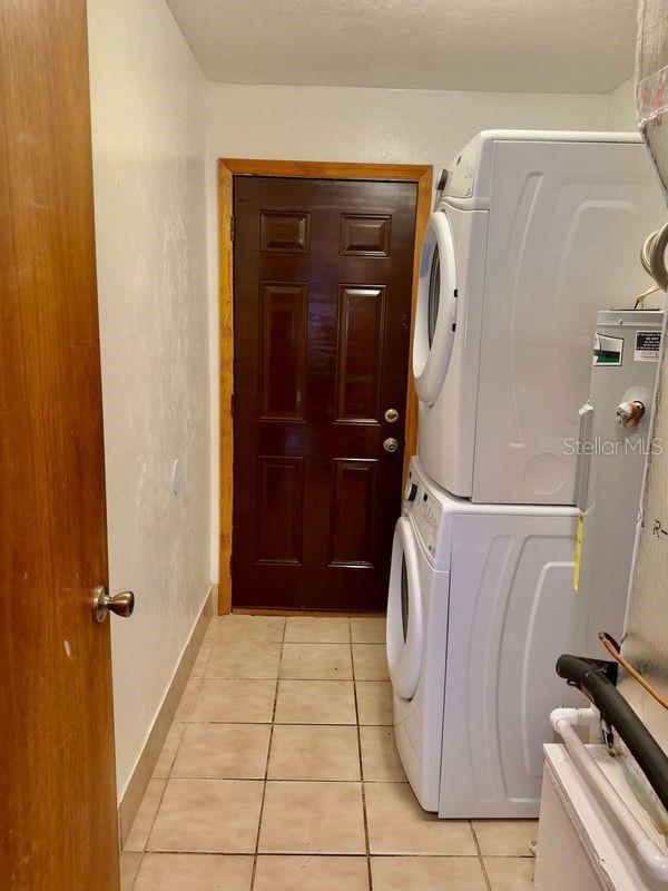 laundry area featuring stacked washing maching and dryer and light tile patterned floors