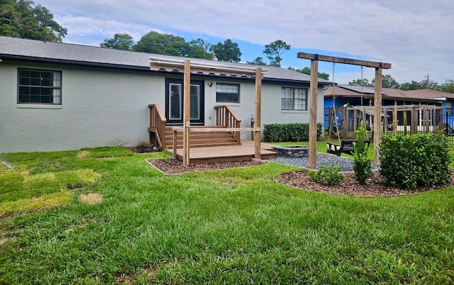 back of property with a deck and a lawn