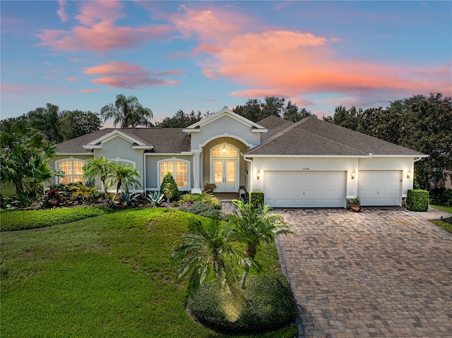 ranch-style home featuring a lawn and a garage