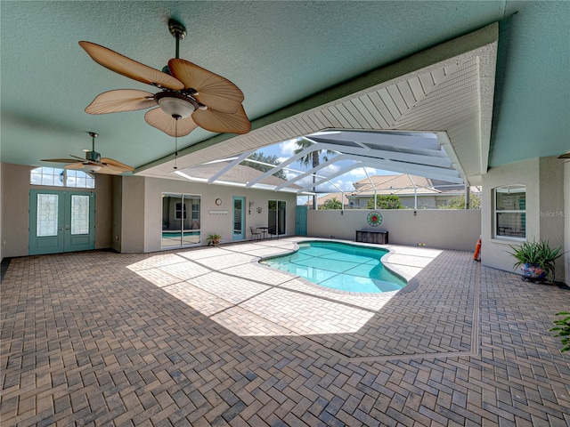 view of swimming pool featuring a patio area, glass enclosure, and ceiling fan