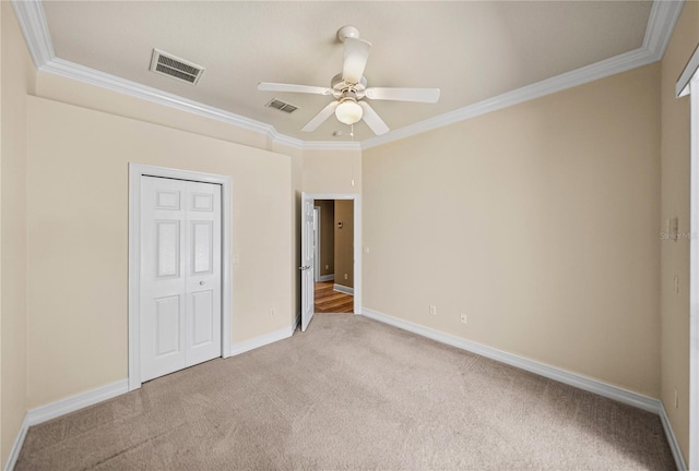 unfurnished bedroom featuring crown molding, light colored carpet, a closet, and ceiling fan