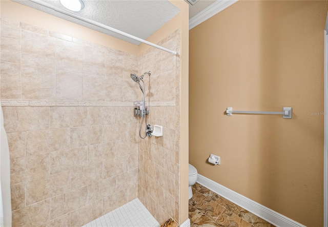 bathroom featuring toilet, ornamental molding, a tile shower, and tile patterned floors