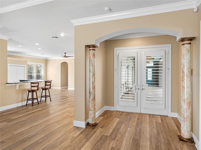 doorway to outside with ornamental molding, ornate columns, and light hardwood / wood-style floors