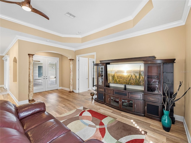 living room featuring ornamental molding, ceiling fan, light wood-type flooring, and decorative columns