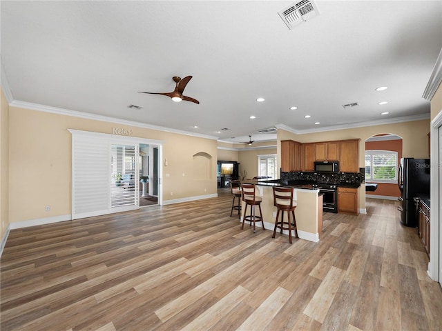 kitchen with ornamental molding, black appliances, and light wood-type flooring