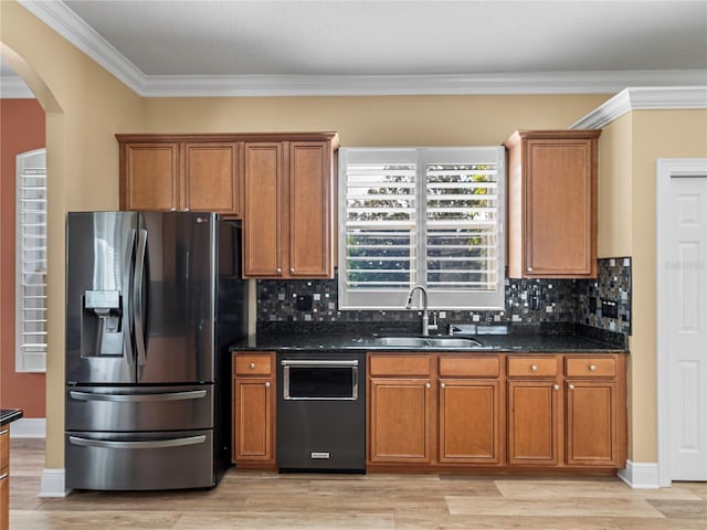 kitchen featuring sink, light wood-type flooring, stainless steel appliances, dark stone counters, and decorative backsplash