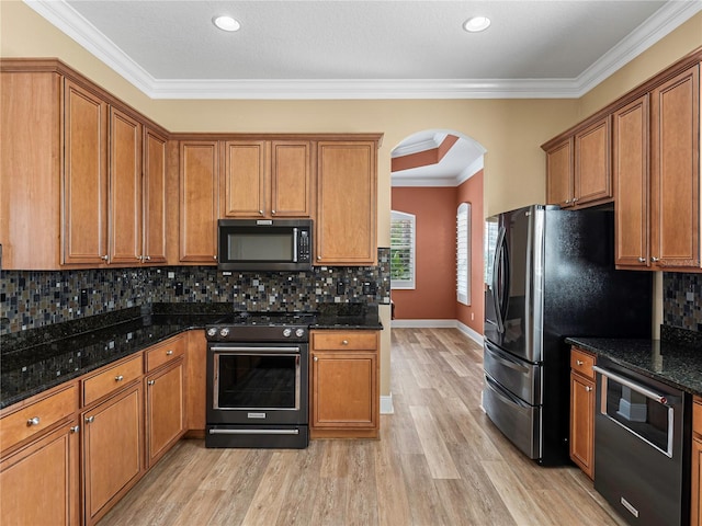 kitchen featuring range with electric stovetop, backsplash, dark stone counters, crown molding, and light hardwood / wood-style floors