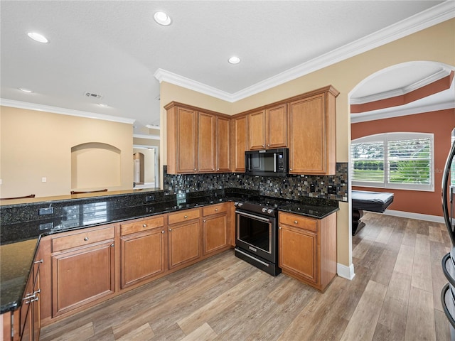 kitchen featuring tasteful backsplash, ornamental molding, dark stone countertops, electric stove, and light hardwood / wood-style floors