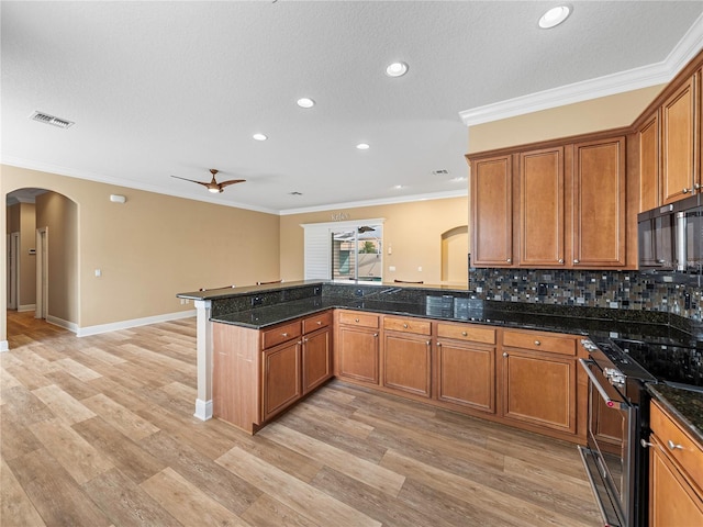 kitchen with stainless steel range, kitchen peninsula, ornamental molding, and light hardwood / wood-style flooring