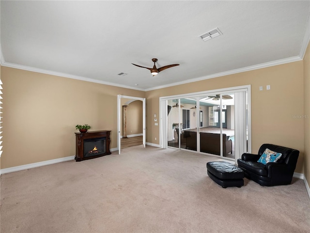 sitting room featuring ornamental molding, light carpet, and ceiling fan