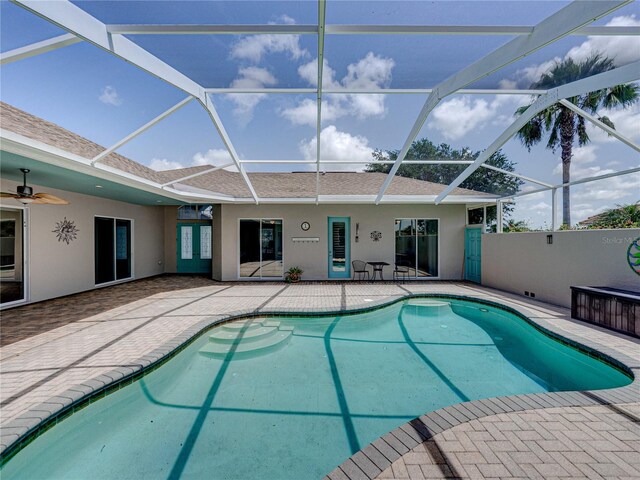 view of pool featuring a patio, glass enclosure, and ceiling fan