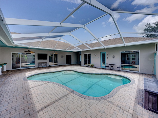 view of swimming pool with a patio area, ceiling fan, and glass enclosure