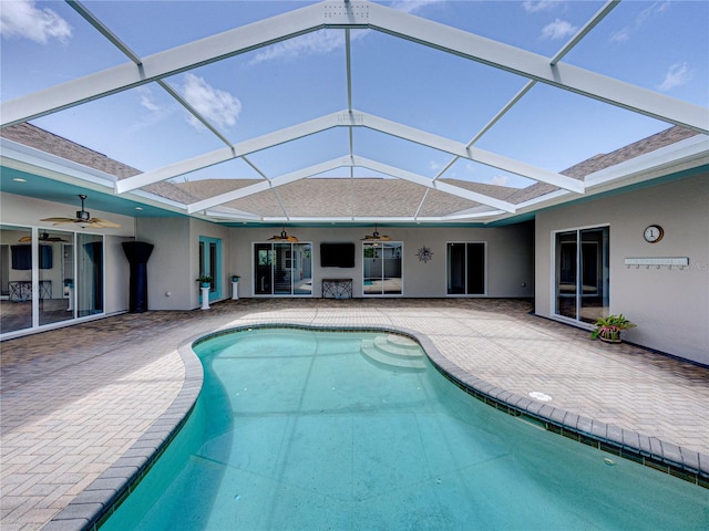 view of pool with a patio, glass enclosure, and ceiling fan