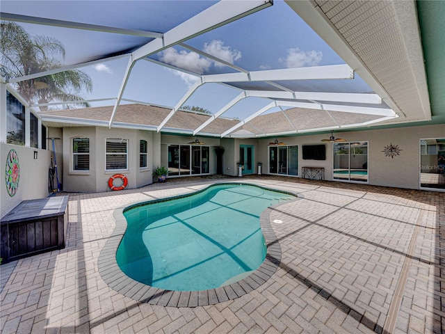 view of swimming pool with a patio, ceiling fan, and glass enclosure