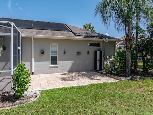 rear view of house with a yard, a patio, and solar panels