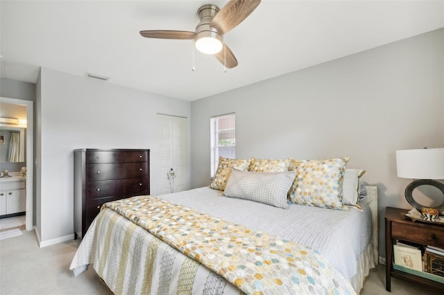 bedroom with a closet, ceiling fan, sink, light colored carpet, and ensuite bathroom