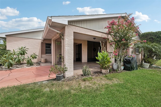 back of property featuring a lawn and stucco siding