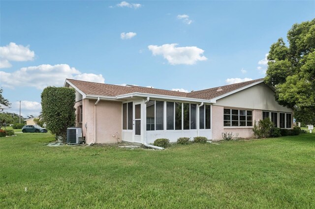 rear view of property featuring a sunroom, a lawn, and central AC unit