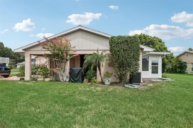 back of property featuring central AC and a lawn