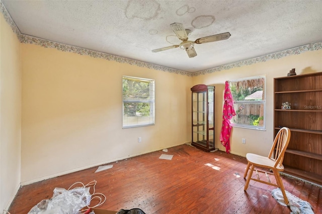 living area featuring wood-type flooring, ceiling fan, and a textured ceiling