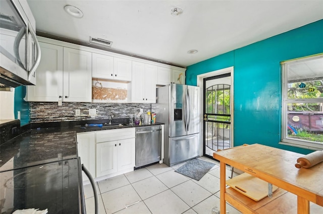 kitchen featuring appliances with stainless steel finishes, sink, a wealth of natural light, and white cabinets