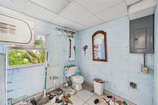 bathroom with tile patterned flooring, toilet, a drop ceiling, and electric panel