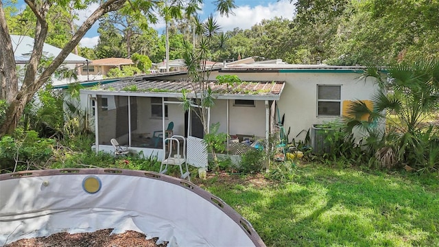 rear view of property with central AC unit, a sunroom, and a lawn